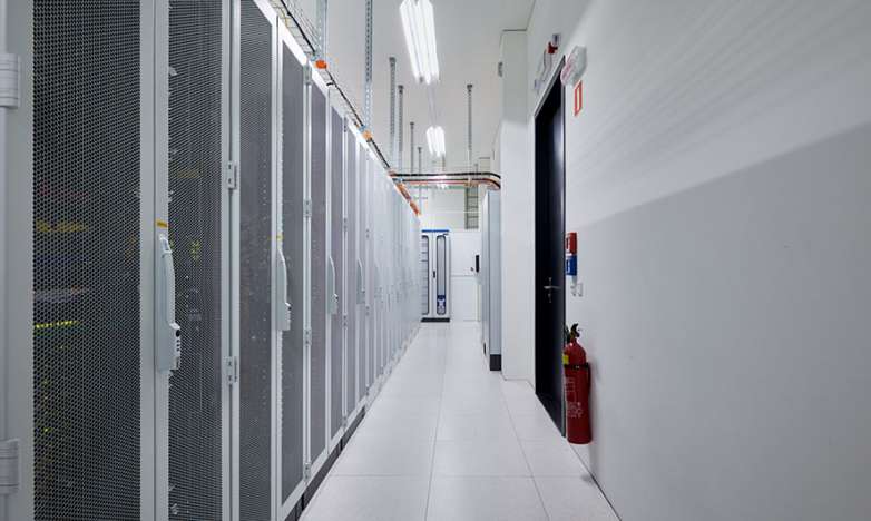 On the left side is a white row of shared server cages. On the right side there is a door with a fire extinguisher.